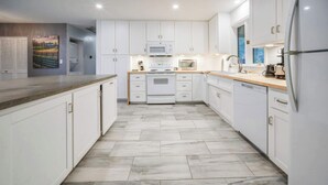 A modern kitchen with white cabinets, a microwave, stove, and a refrigerator.