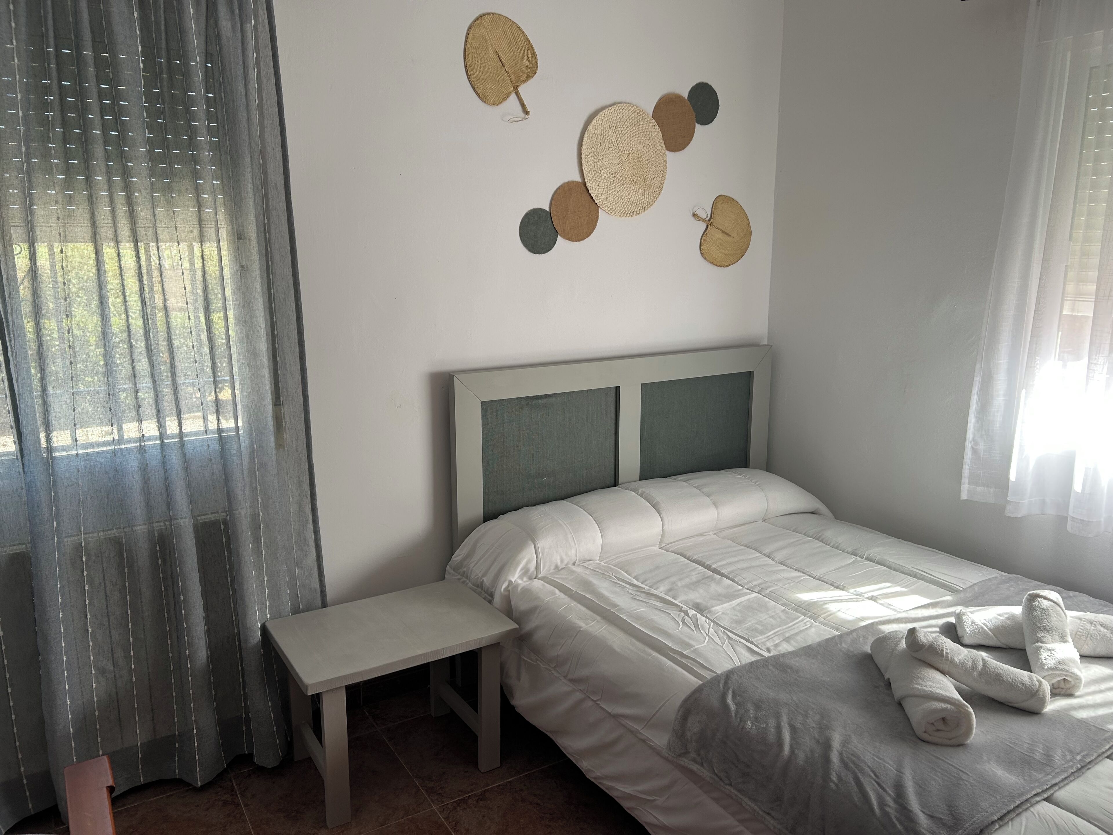 A bedroom with a bed, a bedside table, and a wall decoration.