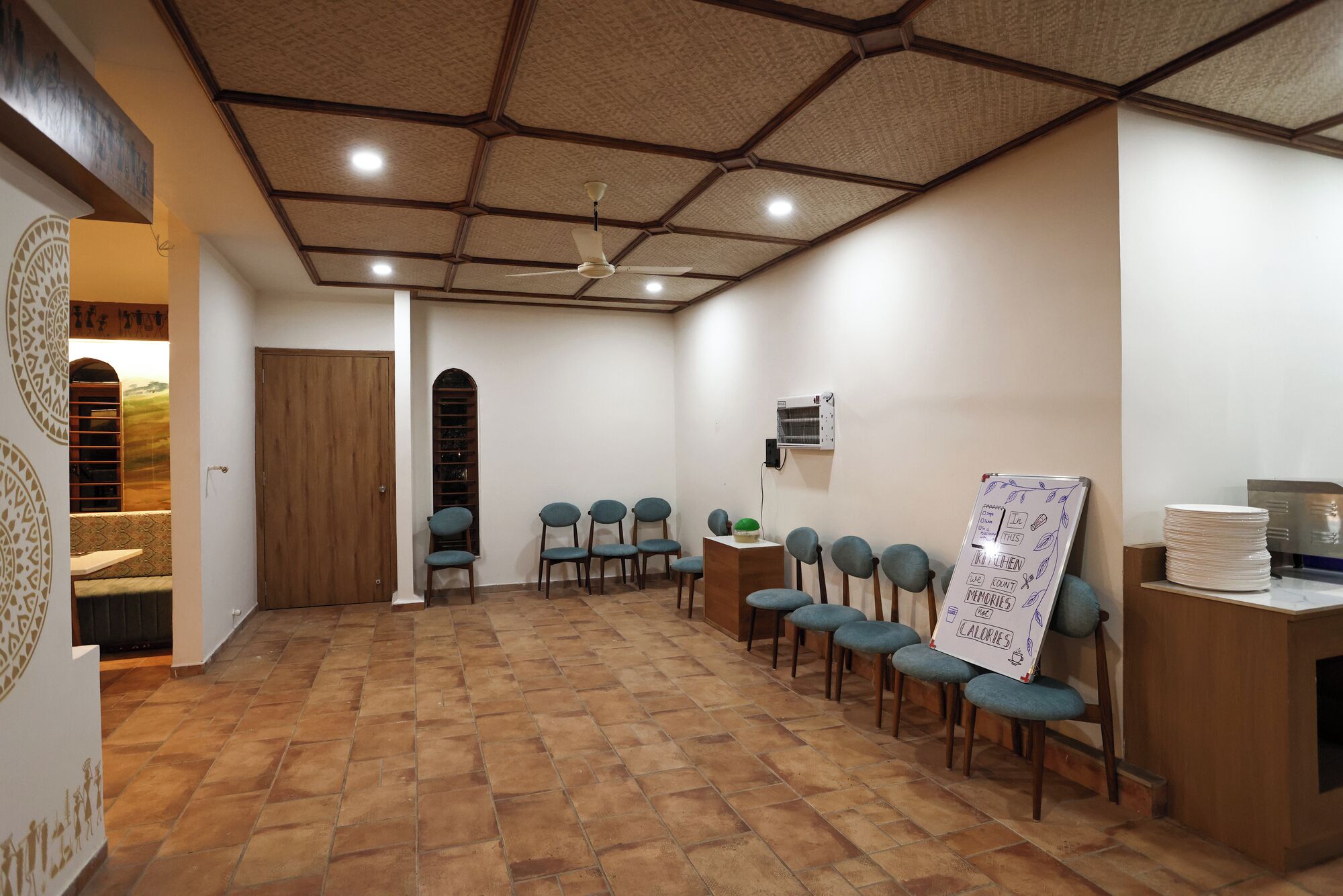 A conference room with a hexagonal ceiling, a wooden door, a window, and a whiteboard with a calorie counter.