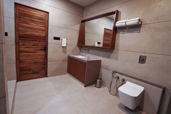 A bathroom with a wooden door, a sink, a mirror, and a toilet. - Le Casa Lion Resort - A Premium Resort In Sasan Gir (Talala)