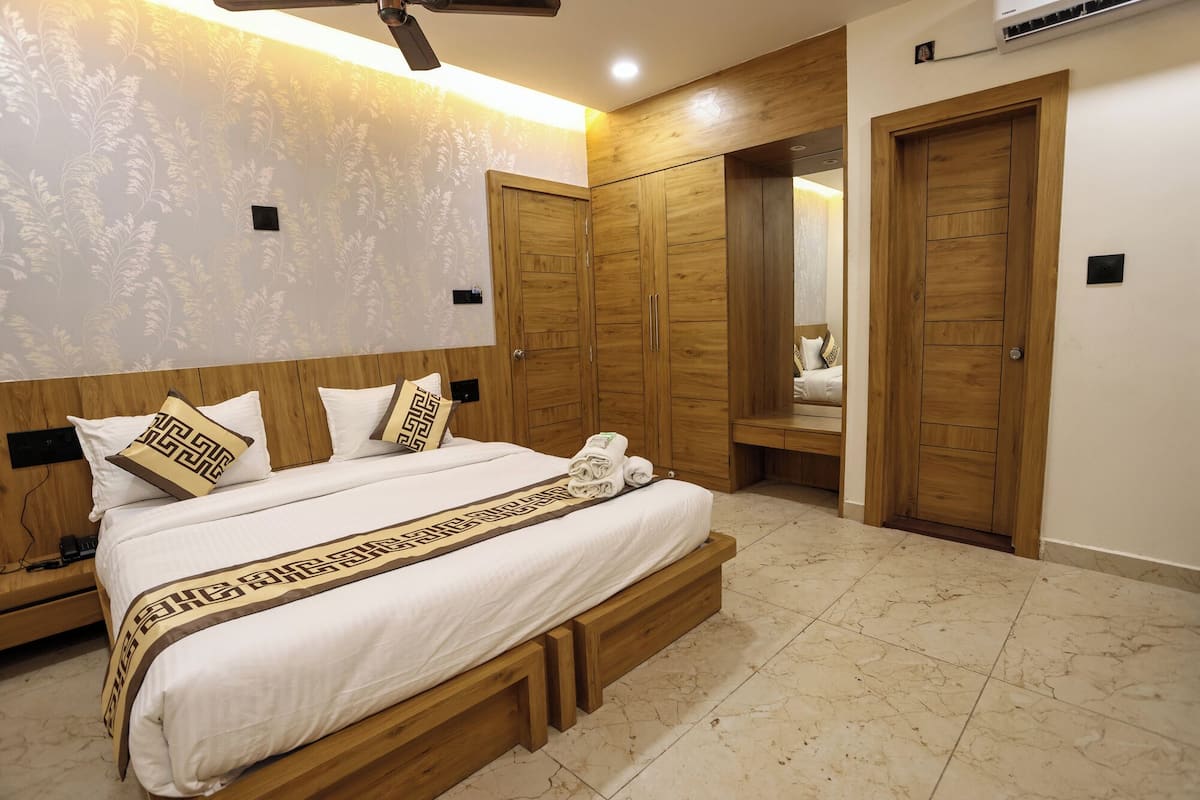 Quarto com uma cama grande, guarda-roupa de madeira e um espelho.