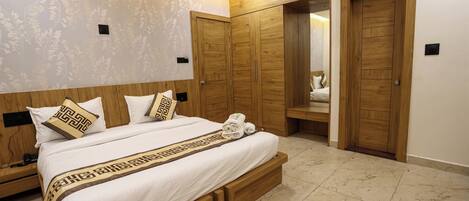 A bedroom with a large bed, wooden wardrobe, and a mirror.