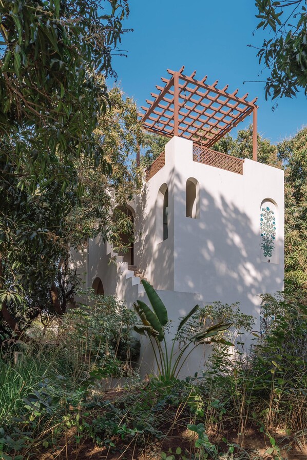 Un bâtiment blanc doté de fenêtres en arc de cercle et d’une pergola en bois.