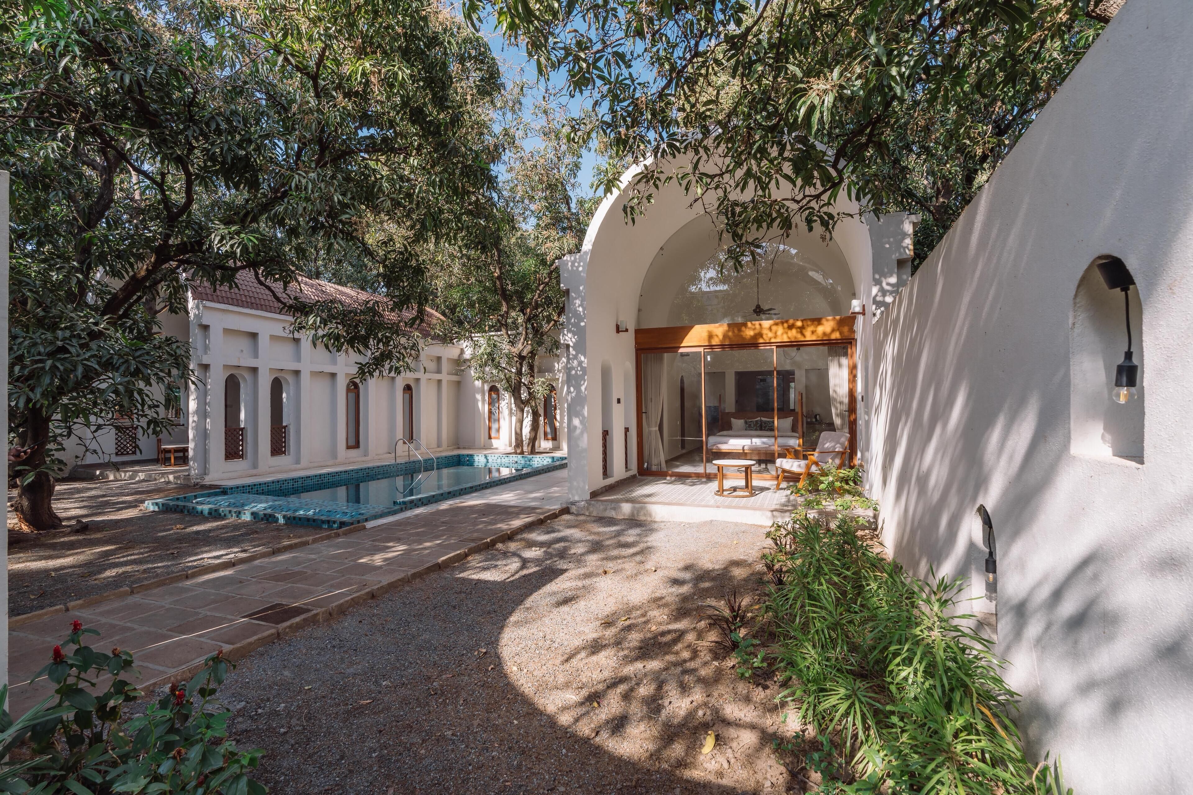 Ein Innenhof mit Swimmingpool, überdachter Sitzgelegenheit und einem Gebäude mit Bögen.
