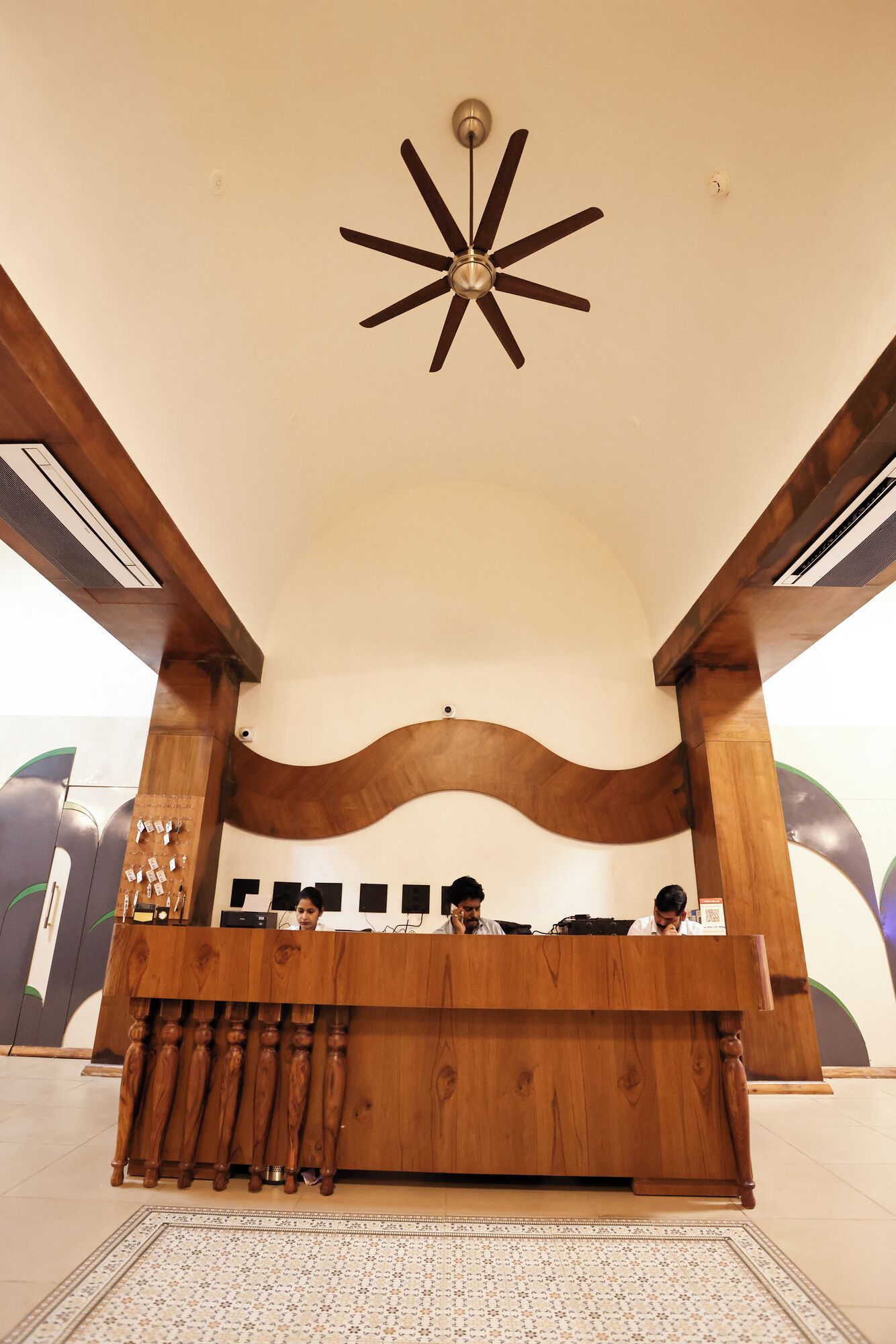 A reception desk with a wooden finish, a ceiling fan, and a decorative light fixture.