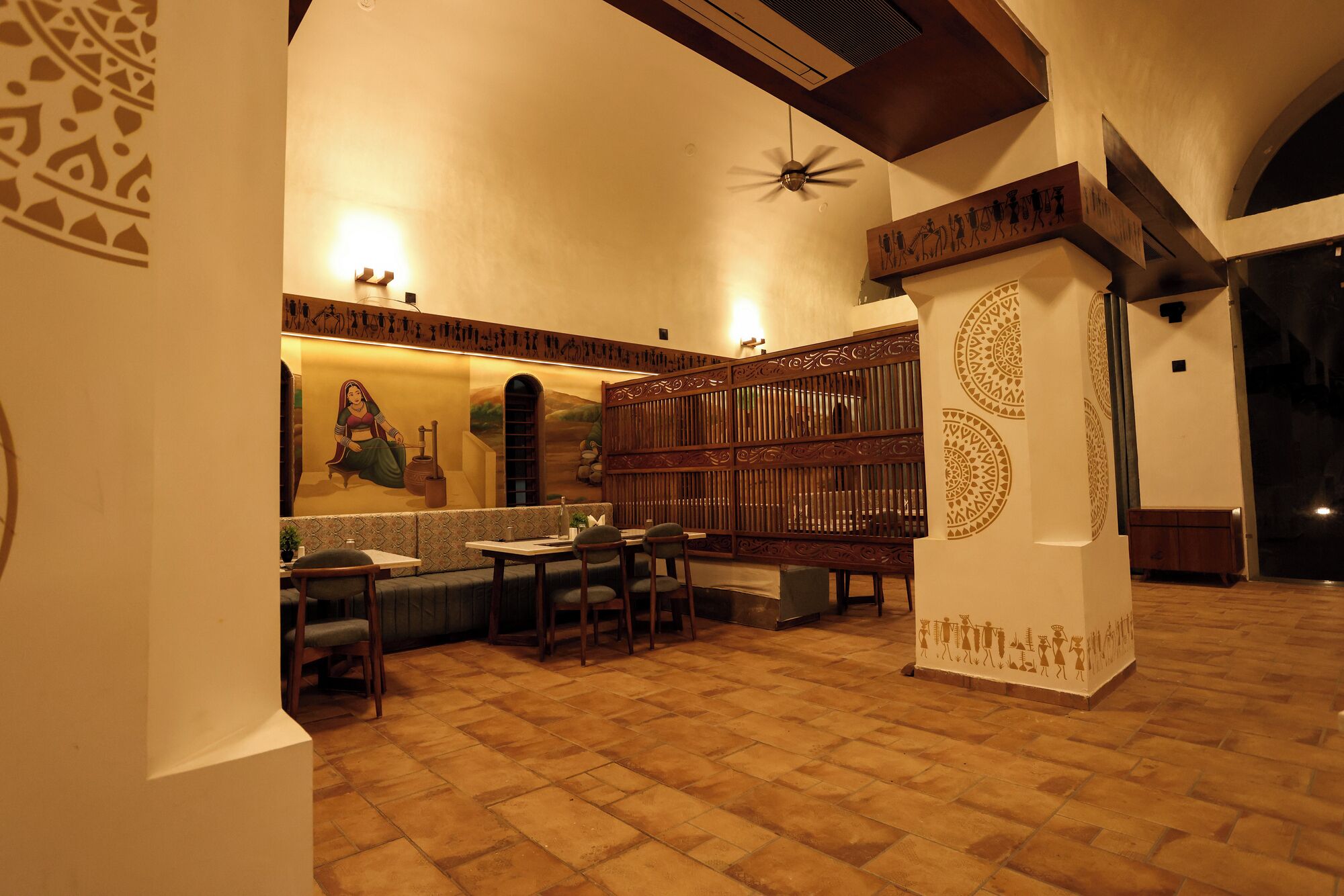 A traditional interior with a high ceiling, patterned walls, and a central seating area with tables and chairs.