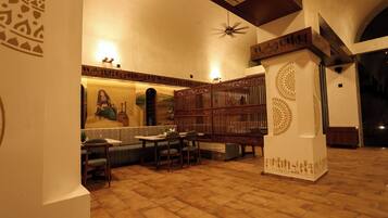 A traditional interior with a high ceiling, patterned walls, and a central seating area with tables and chairs.