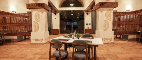 A dining area with a long table, four chairs, and decorative wall panels.