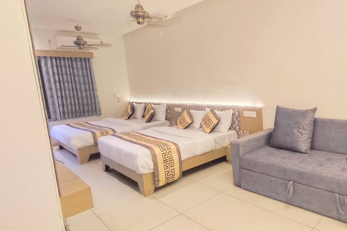 Quarto de hotel com uma cama, um sofá e um ventilador de teto.