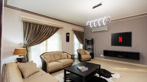 A modern living room with a sofa, armchair, coffee table, and a flat-screen TV mounted on the wall.