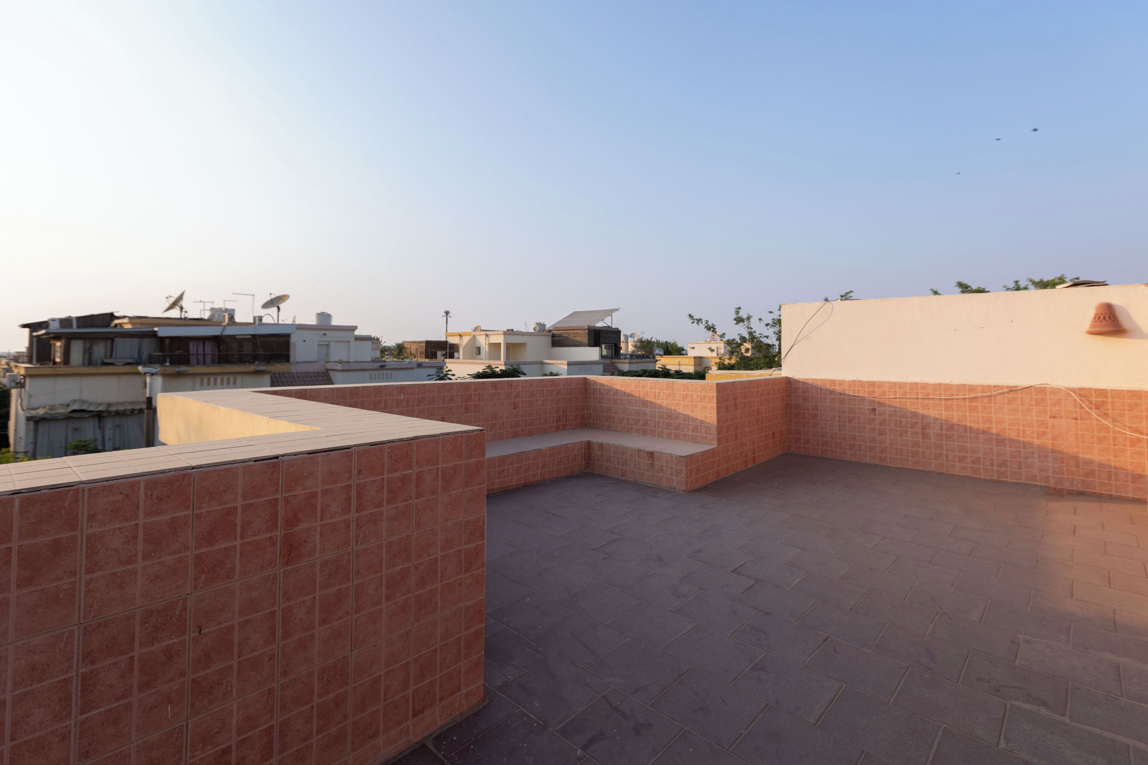 A rooftop terrace with tiled flooring and a seating area.