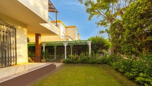 A modern building with a covered patio, a well-maintained lawn, and surrounding greenery.