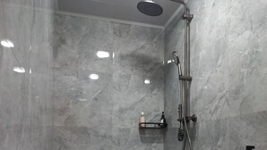 Une salle de bain moderne avec une douche, des murs en marbre et des toilettes.
