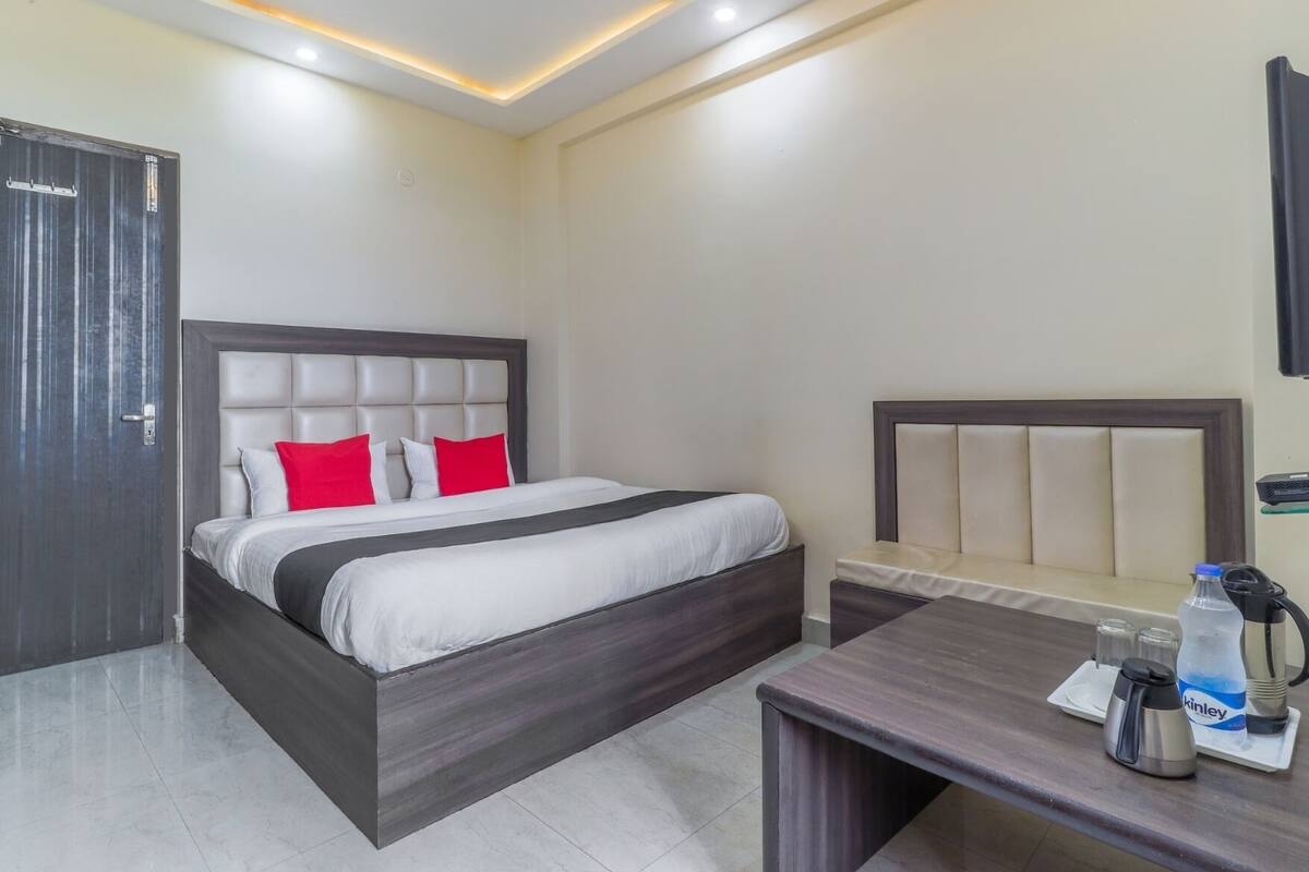 A hotel room with a bed, bedside table, and a small seating area.