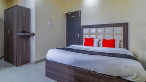 A hotel room with a large bed, a wardrobe, and a door. - Hotel Mahadeva Regency (Kanpur)