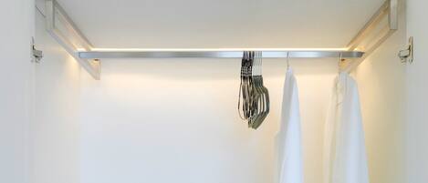 A white walk-in closet with a hanging rack and a folded towel on the floor.
