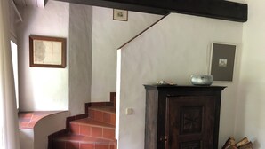 Eine Treppe mit roten Fliesen führt zu einem dunklen Holzschrank, auf dem ein Radio steht.