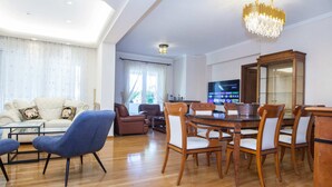 Ein geräumiges Wohnzimmer mit einem modernen Sofa, einem Esstisch mit Stühlen und einer großen Holzkommode.