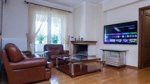 Ein Wohnzimmer mit Ledersofas, einem Glastisch und einem an der Wand montierten Flachbildfernseher.