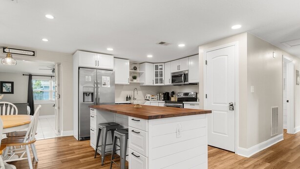 A modern kitchen with white cabinetry, a wooden countertop island, and stainless steel appliances. - GameRoom+Dogs+4 BR+Kids+FAST WIFI + 2 Kings (Panama City)