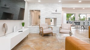 A modern living room with a white brick wall, a fireplace, and a dining area with a glass table.