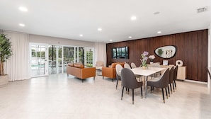 A spacious room with a large dining table, multiple chairs, a sofa, and a television.