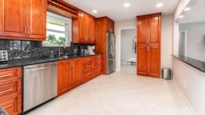 A modern kitchen with wooden cabinets, stainless steel appliances, and a black granite countertop.