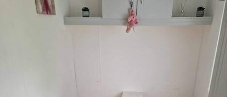 Una habitación pequeña y funcional con dos camas individuales, un armario blanco decorado con motivos rosas y un radiador al pie de las camas.