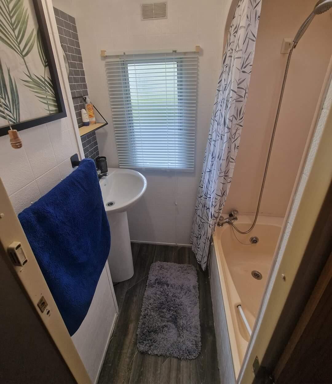 A compact bathroom with a sink, toilet, and shower.
