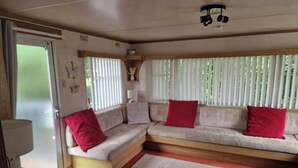 A cozy interior with a sofa set against a window, a lamp, and a ceiling light fixture. - River Bliss in Whelspool (Welshpool)