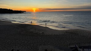 A beach with a sunset, calm sea, and a distant shoreline. - SYDNEYS LEADING NO.1 STAY (Coogee)