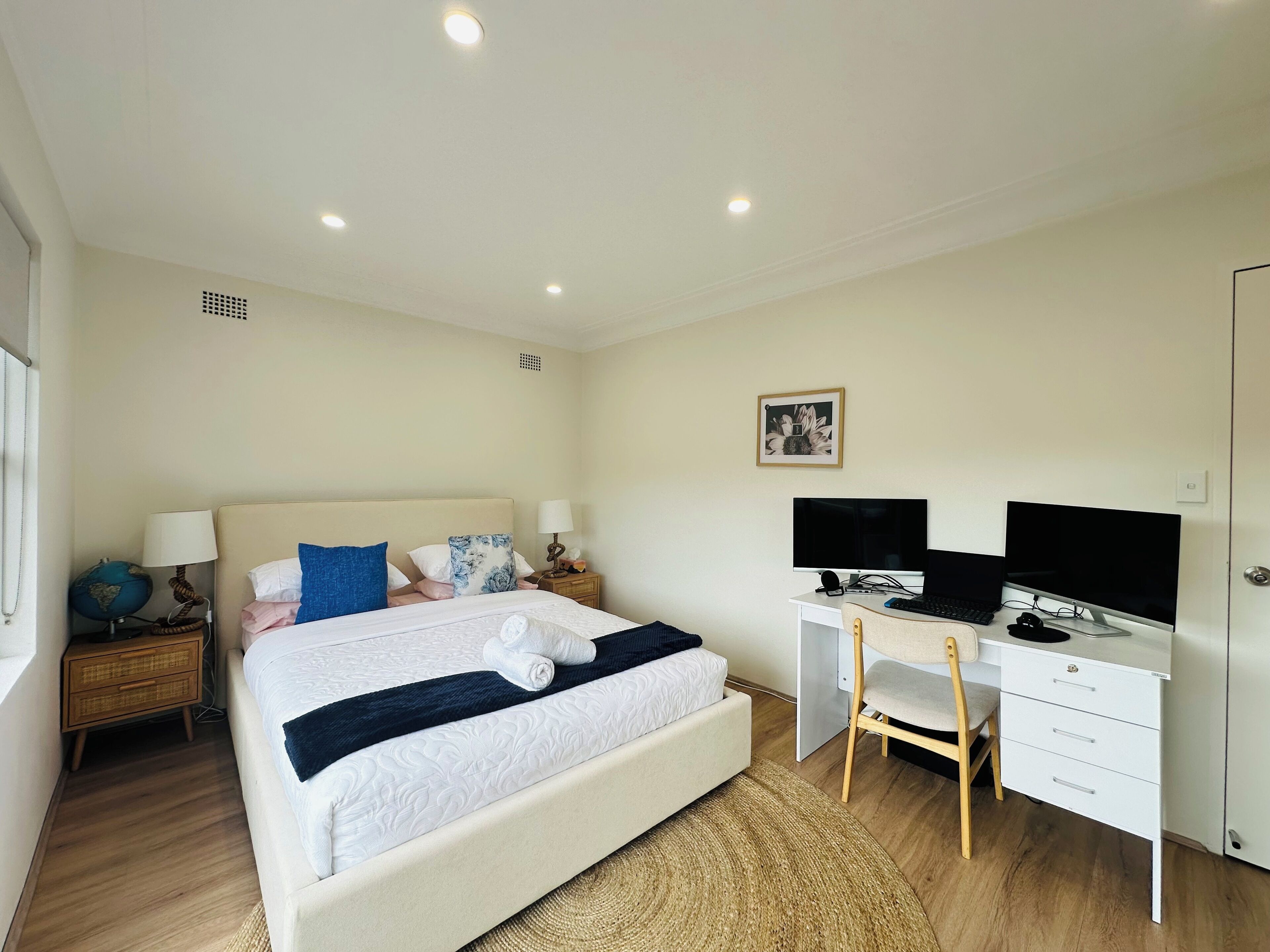 Une chambre à coucher avec un lit, un bureau avec un ordinateur, une télévision et un globe terrestre posé sur une table de chevet.
