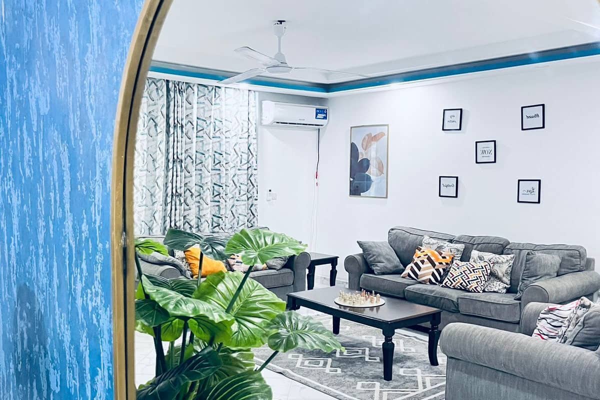 A modern living room with a large mirror, grey sofas, a coffee table, and a potted plant.