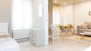 A modern bedroom with a bed, a desk, and a seating area with chairs.
