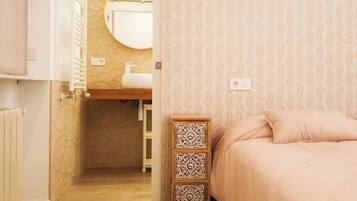 Cozy retreat with a simple bed, bedside table, and wall-mounted mirror.