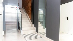 A modern interior with a staircase, a glass railing, and a door.