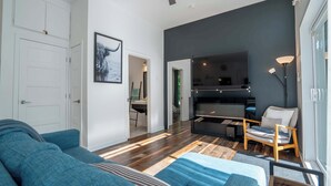 A modern living room with a blue sofa, a wooden coffee table, and a large window. - Absolute comfort with Spa | Chalet le Petit Castor (Chertsey)