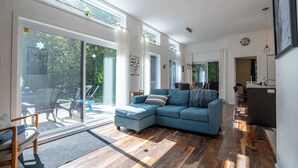 A modern living room with a sectional sofa, a dining area, and a kitchen. - Absolute comfort with Spa | Chalet le Petit Castor (Chertsey)