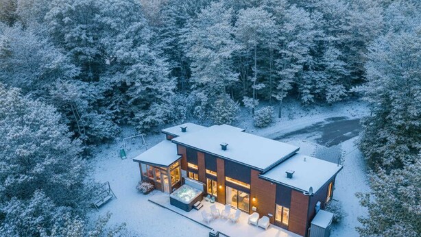 A modern house with a patio area, large windows, and a hot tub. - Absolute comfort with Spa | Chalet le Petit Castor (Chertsey)