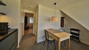 Una cucina moderna con zona pranzo, che include un tavolo e sedie in legno, una lampada a sospensione e una scala che conduce a un altro piano.