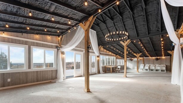 A spacious hall with large windows, a high ceiling with exposed beams, and a chandelier. - Valley View Cottage (Omaha)