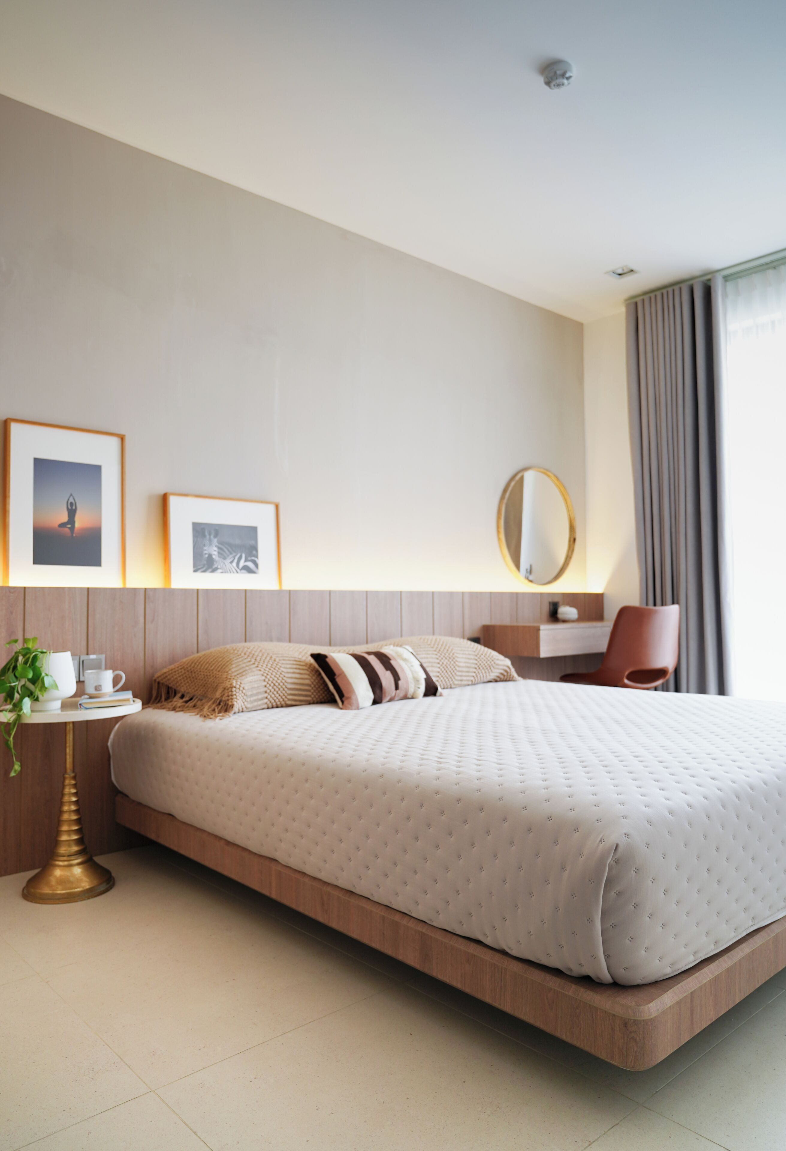 A modern hotel room with a large bed, bedside table, and a chair.