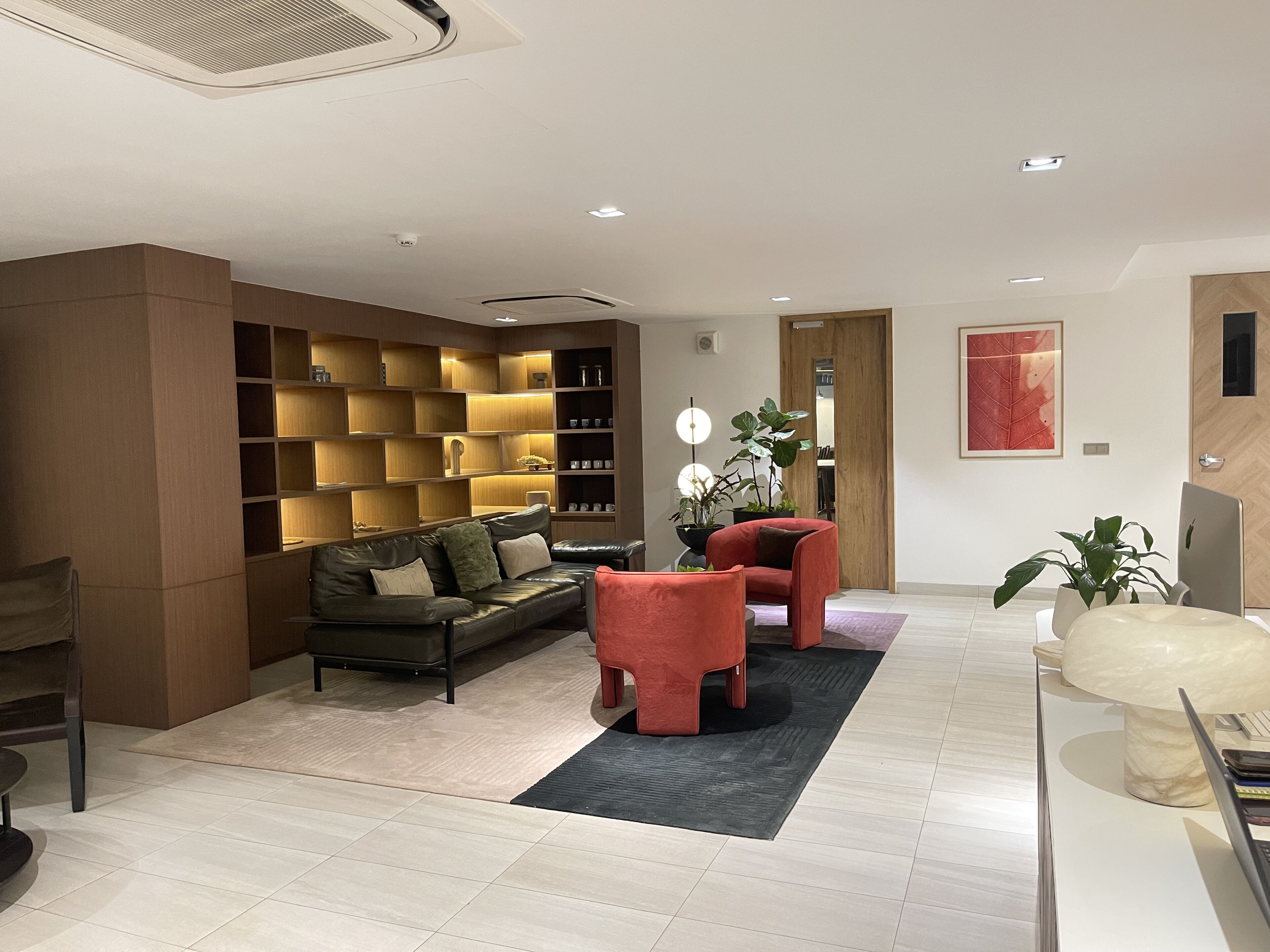 A modern living room with a sectional sofa, a red armchair, a coffee table, and a bookshelf.