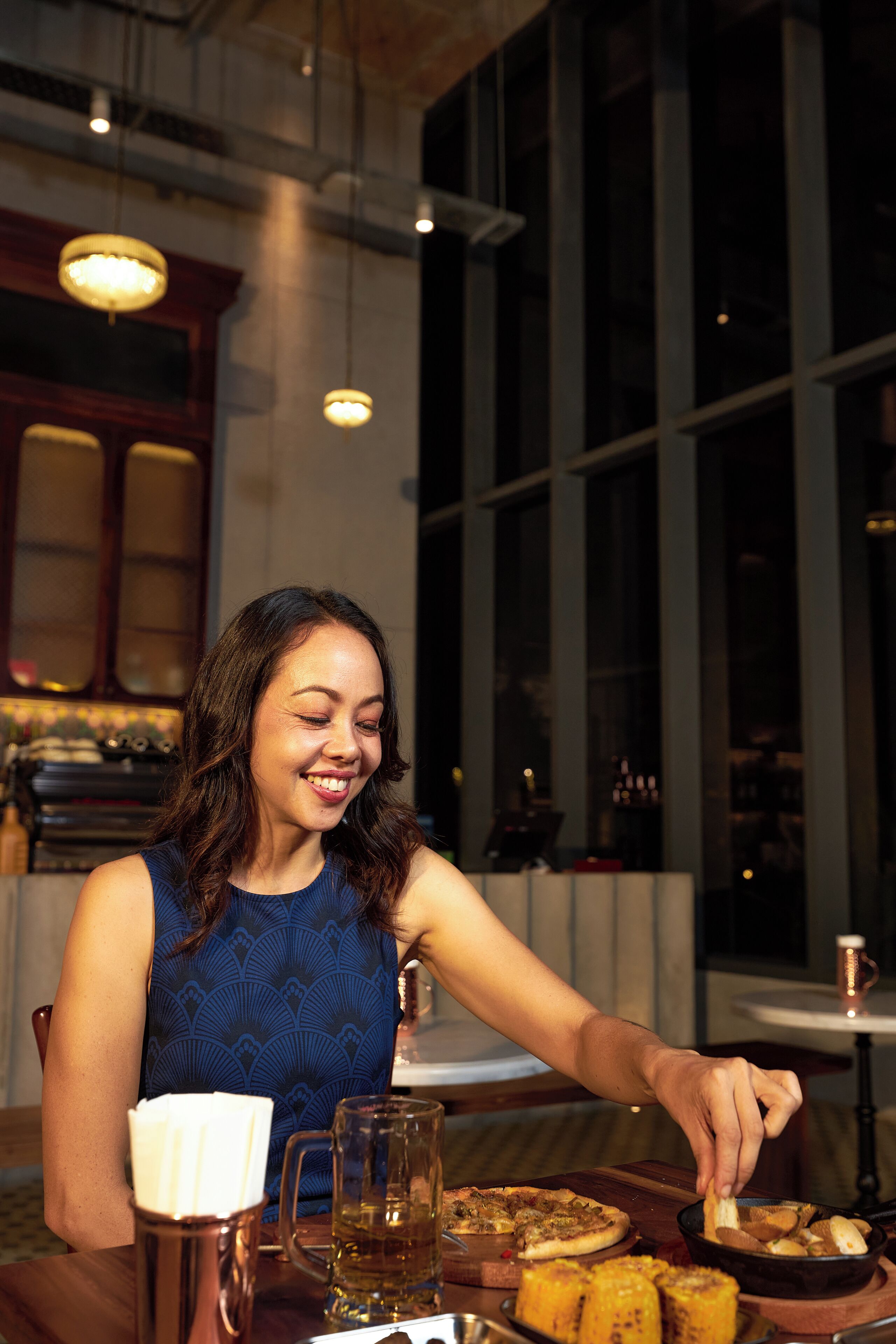A person seated at a table with a meal, a drink, and a napkin.