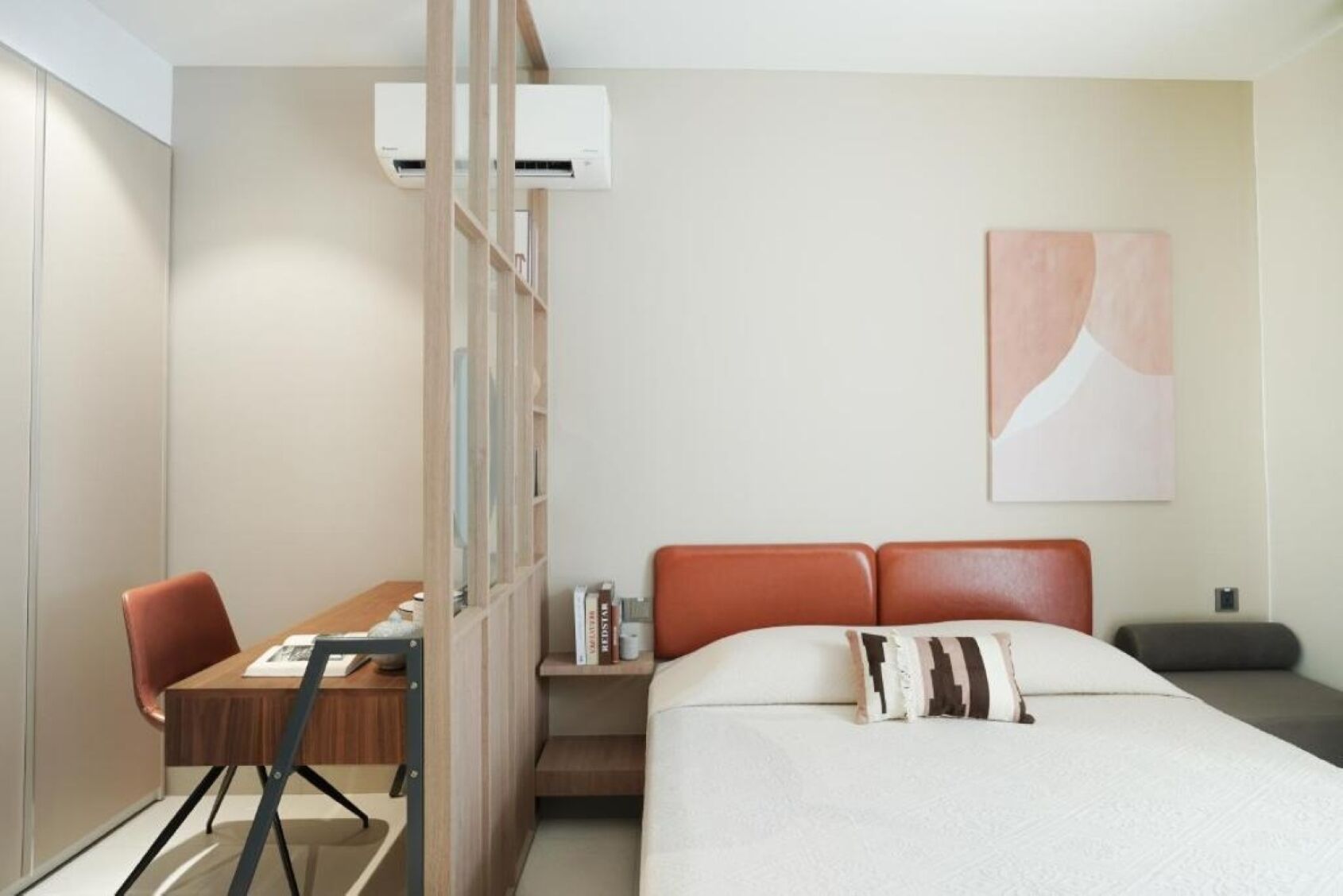Ein modernes Hotelzimmer mit Bett, Schreibtisch, Stuhl, Bücherregal und einem Gemälde an der Wand.