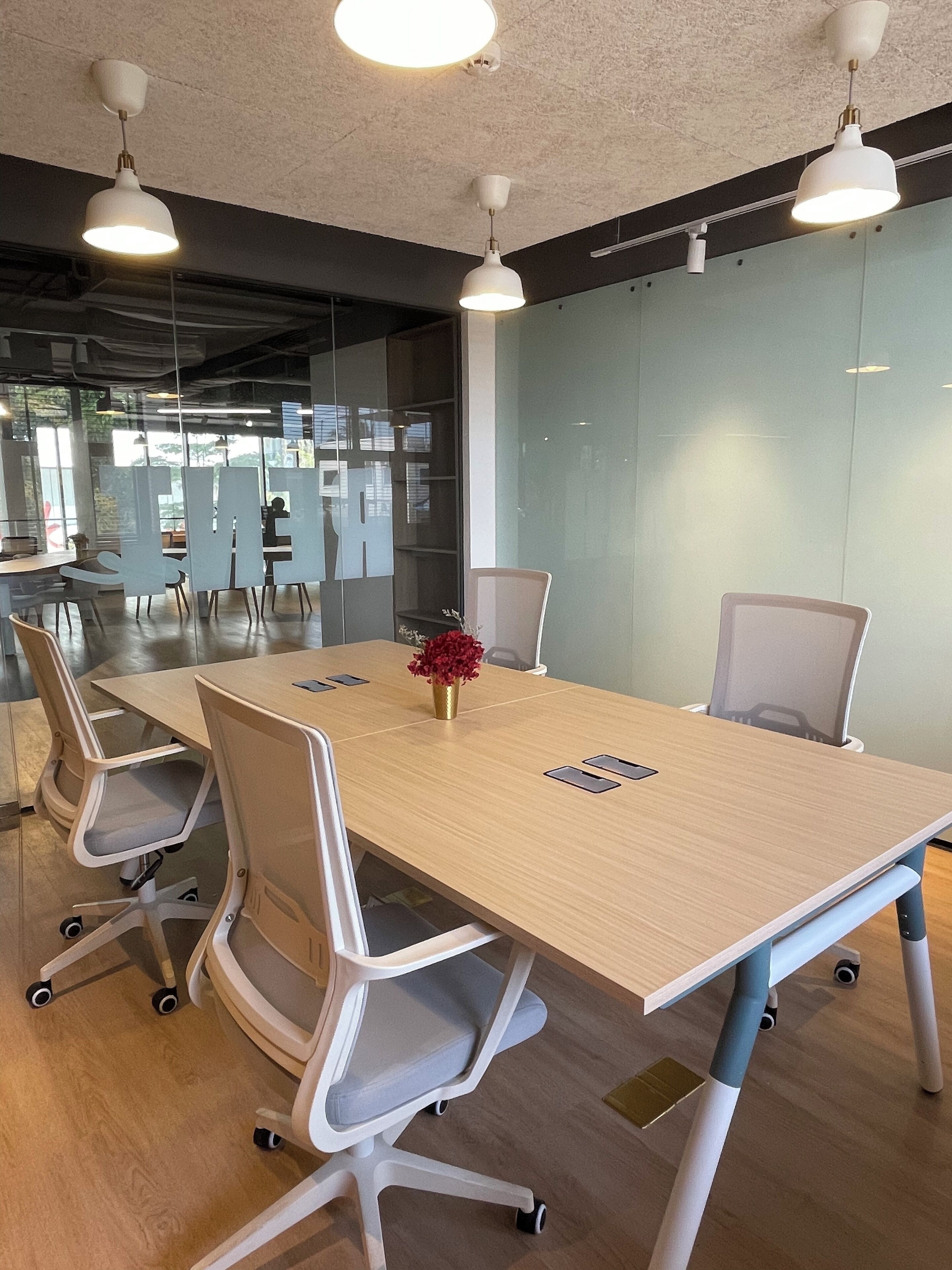 A conference room with a long table, white chairs, and pendant lighting.