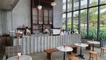 Ein modernes Café mit Barbereich, runden Tischen und Blick auf Grünflächen.