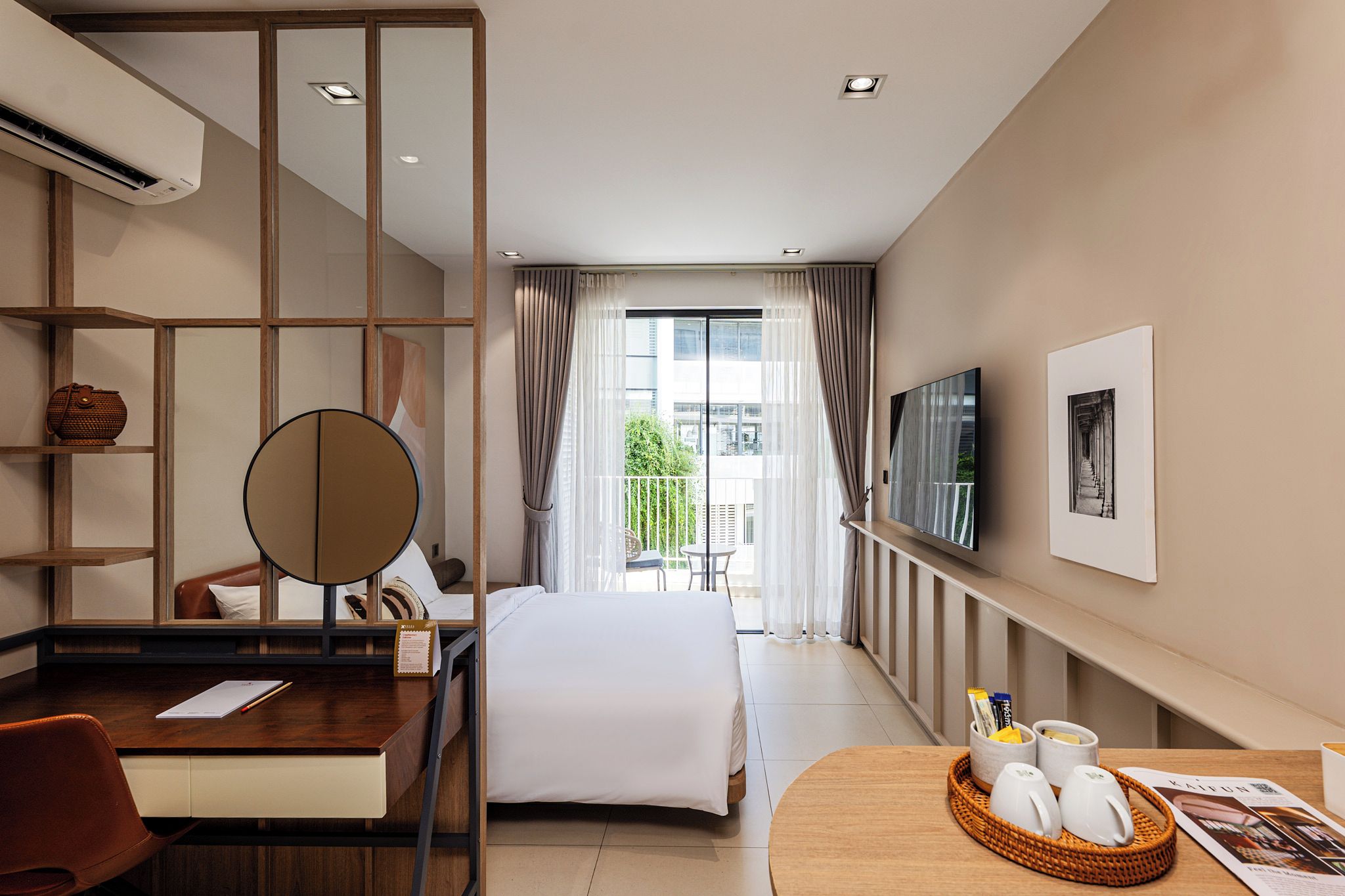 A hotel room with a bed, a desk with a chair, a TV, and a view of the outdoors.