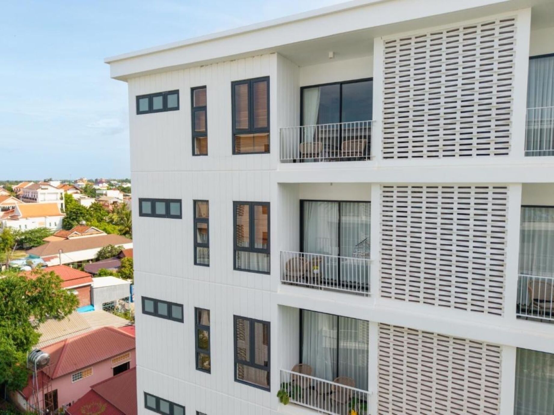 Un immeuble à plusieurs étages, doté de balcons, de grandes fenêtres et d’une façade blanche.