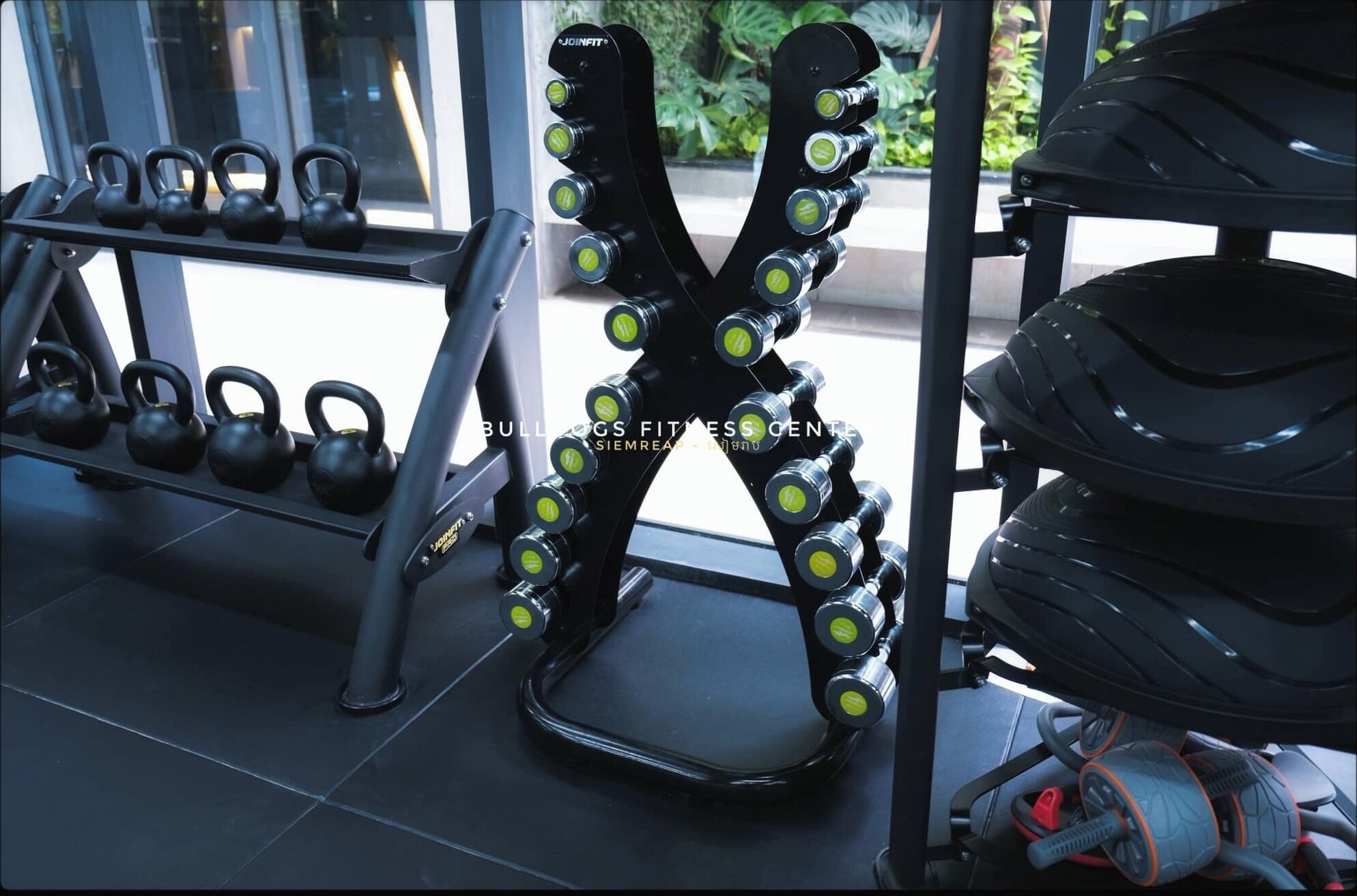 Un gimnasio con pesas rusas, mancuernas y una cinta de correr.